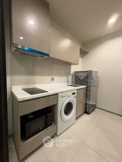 Modern kitchen with sleek appliances including washing machine and microwave, perfect for urban living.