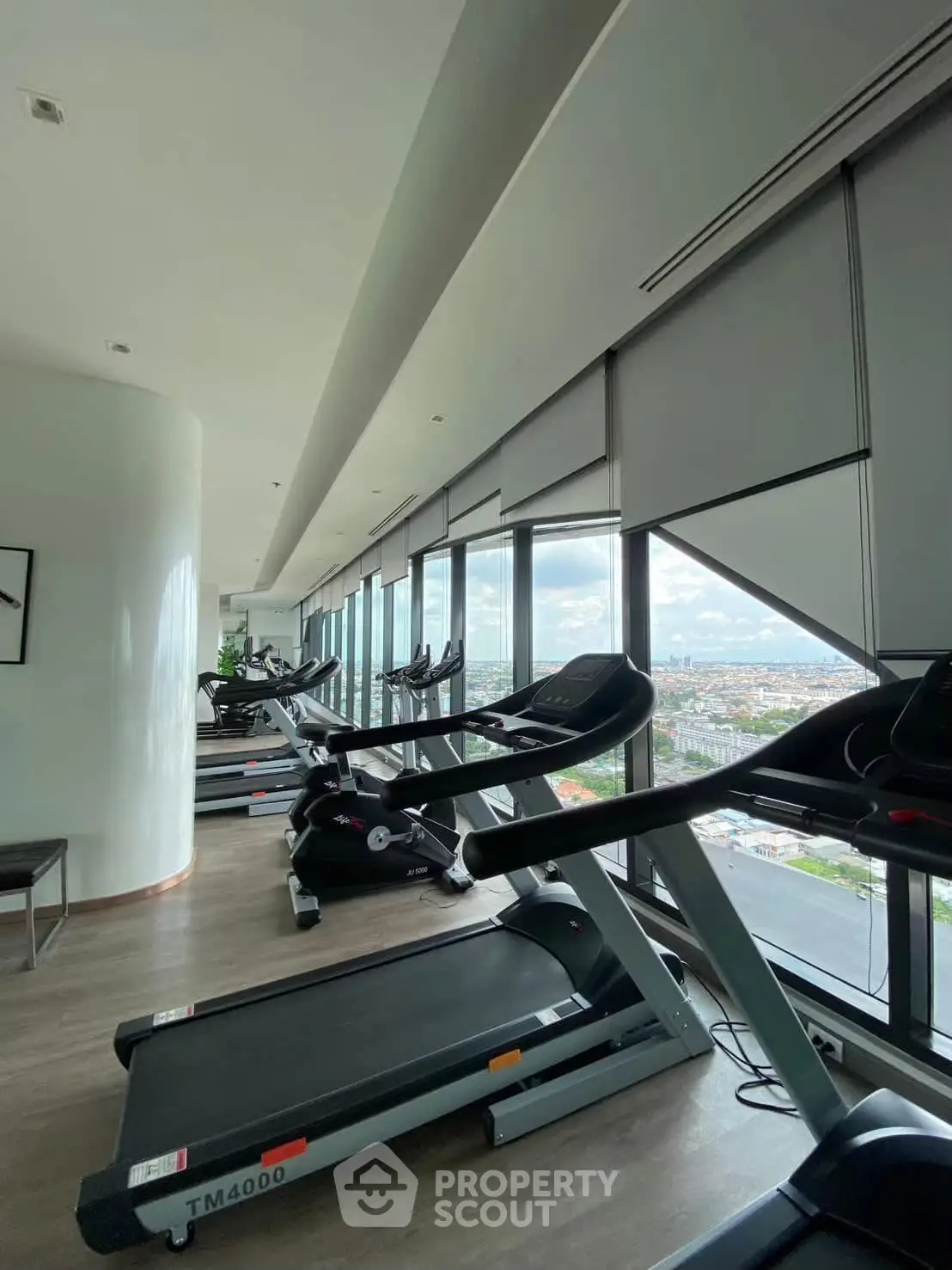 Modern gym with panoramic city views and state-of-the-art equipment in luxury high-rise building.