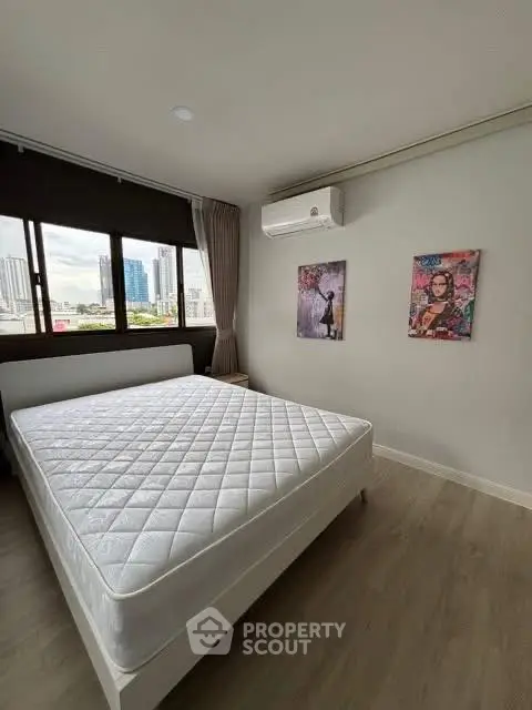 Spacious bedroom with city view and modern decor in urban apartment.