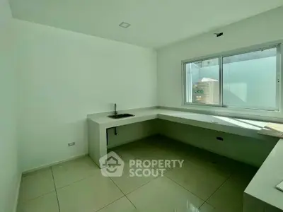 Modern minimalist kitchen with sleek countertops and large window