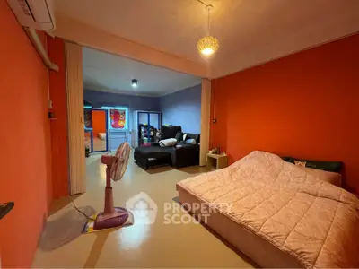 Spacious bedroom with vibrant orange walls and cozy furnishings