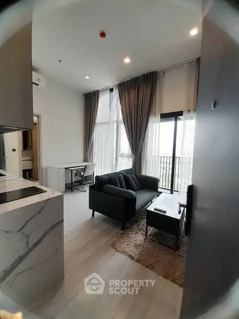 Modern living room with high ceilings and large windows in a stylish apartment.