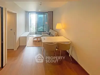 Modern living room with cozy seating and large window offering city views.