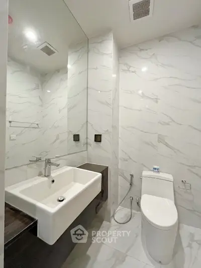 Modern bathroom with sleek white fixtures and marble walls