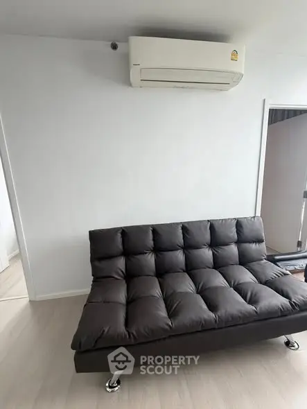 Modern living room with sleek black sofa and wall-mounted air conditioner, perfect for urban living.