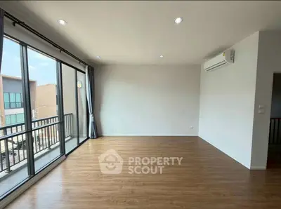 Spacious living room with large windows and wooden flooring in modern apartment