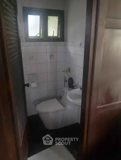 Cozy bathroom with modern toilet and small window, ideal for compact spaces.