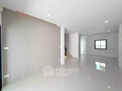 Spacious modern living room with sleek tile flooring and neutral walls, perfect for customization.