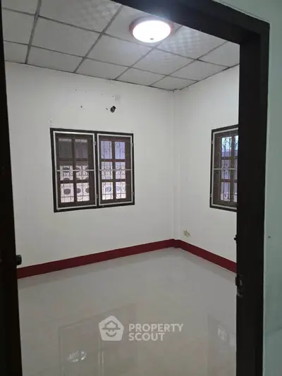 Spacious empty room with tiled floor and two windows, ideal for customization.