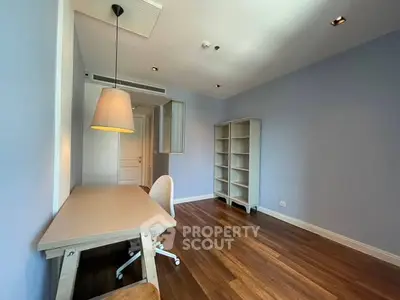 Spacious study room with modern desk and shelving, featuring elegant wooden flooring and soft lighting.