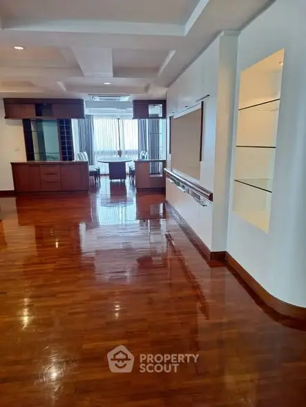 Spacious living room with polished wooden floors and built-in shelves, ideal for modern living.