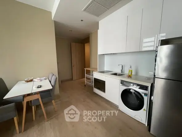 Modern kitchen with sleek appliances and cozy dining area in a stylish apartment.