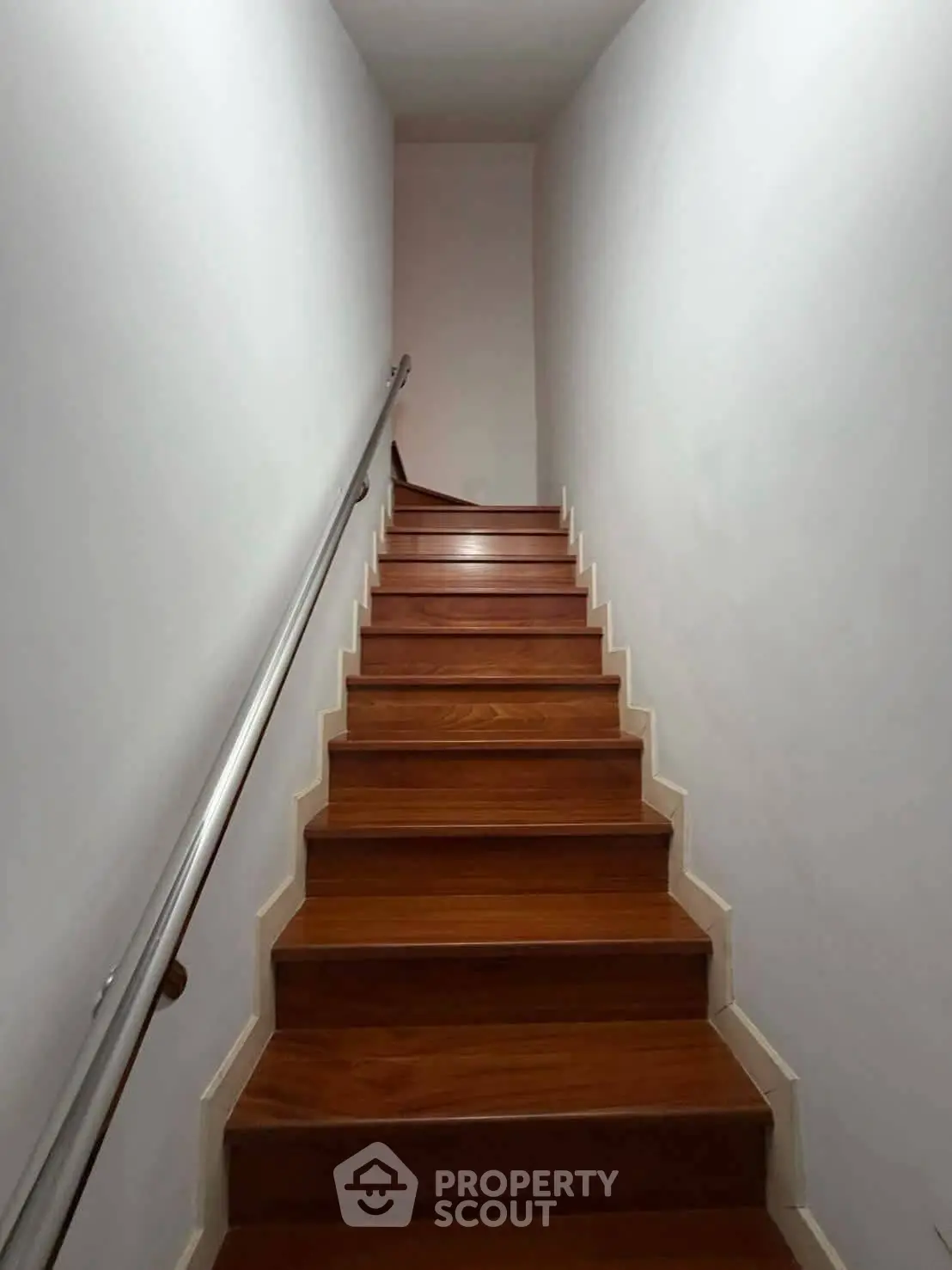 Modern wooden staircase with sleek metal railing in a minimalist interior design
