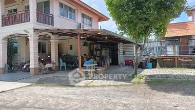 Charming two-story house with spacious carport and outdoor seating area, perfect for family gatherings.