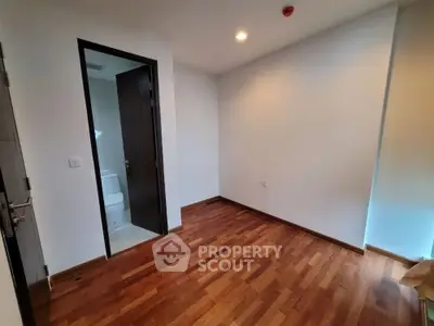 Spacious room with wooden flooring and attached bathroom in modern apartment.