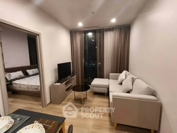 Modern living room with cozy sofa and TV, adjacent to a stylish bedroom, featuring a city view.