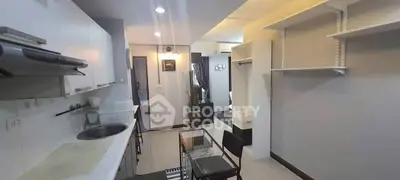 Modern open-layout kitchen with sleek white cabinets and dining area in stylish apartment.