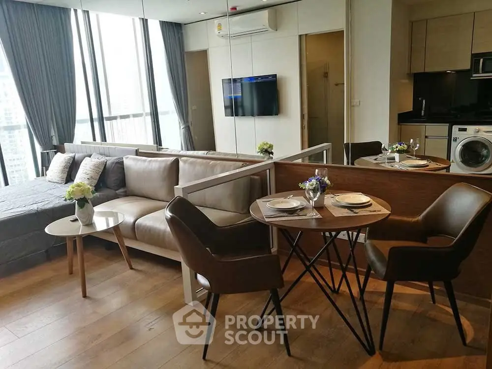 Modern open-plan living room with stylish furniture and large windows in a high-rise apartment.