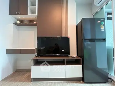 Modern living room with sleek TV setup and refrigerator, ideal for urban living.