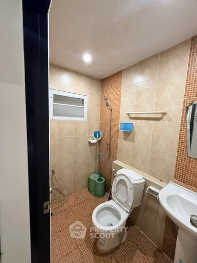 Modern bathroom with tiled walls, shower, and toilet in a real estate property.