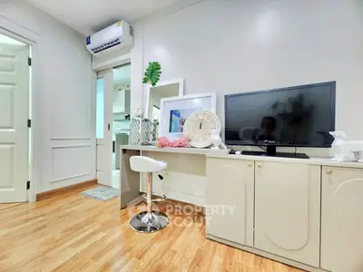 Modern living room with stylish decor and wooden flooring, featuring a TV and elegant furniture.