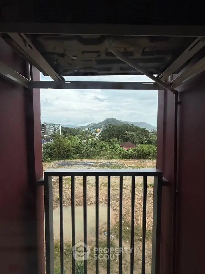 Scenic view from a balcony overlooking lush greenery and distant hills.