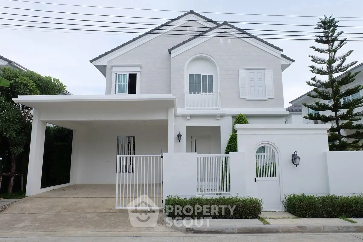 Elegant two-story white house with gated entrance and carport in a serene neighborhood.