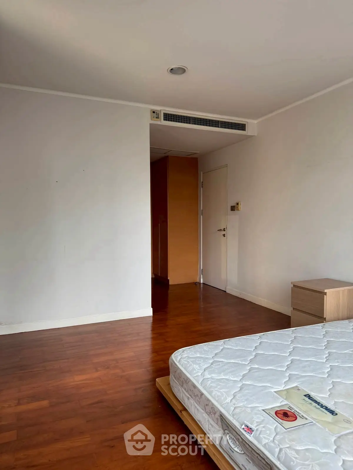 Spacious bedroom with wooden flooring and minimalist design