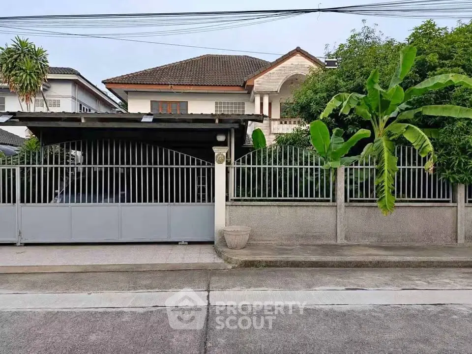 Charming suburban house with lush greenery and secure gated entrance, perfect for family living.