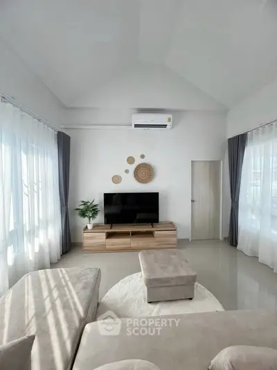 Spacious modern living room with natural light, stylish decor, and cozy seating area.