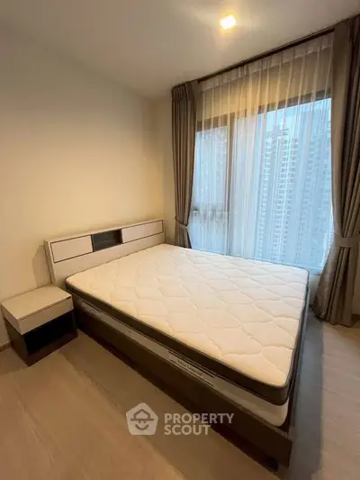 Modern bedroom with large window and city view, featuring a comfortable bed and stylish decor.