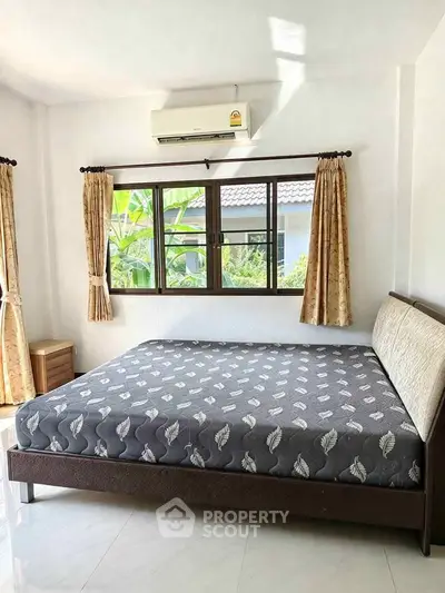 Bright bedroom with large window, air conditioning, and elegant curtains in a modern home.
