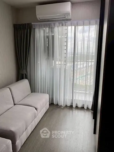 Modern living room with large window and air conditioning, featuring a cozy sofa and elegant curtains.