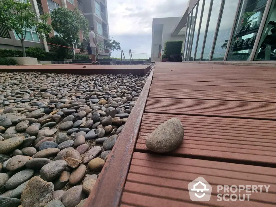 Modern apartment exterior with wooden deck and stone landscaping