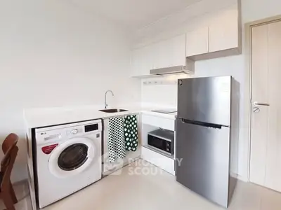 Modern kitchen with washing machine, fridge, and microwave in compact layout.