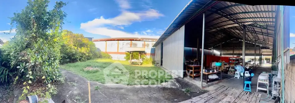 Expansive industrial property with open warehouse and lush greenery, ideal for business operations.