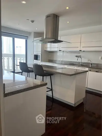 Modern kitchen with sleek white cabinets, granite countertops, and a central island with bar stools.