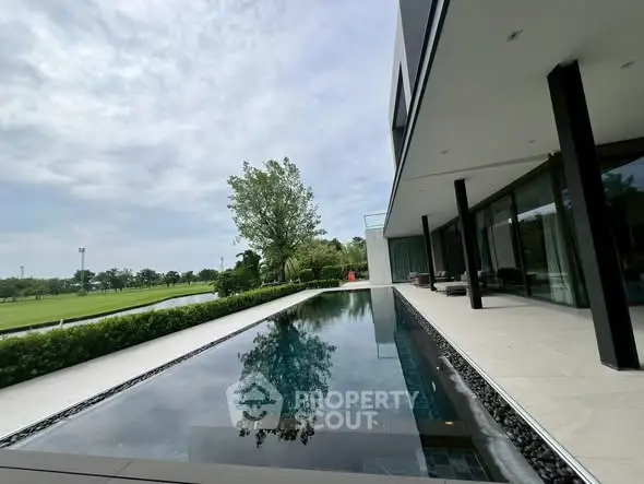 Luxurious modern home with sleek pool and lush greenery, offering serene outdoor living experience.