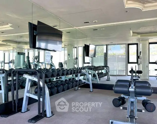 Modern gym with mirrored walls and state-of-the-art equipment in luxury building.