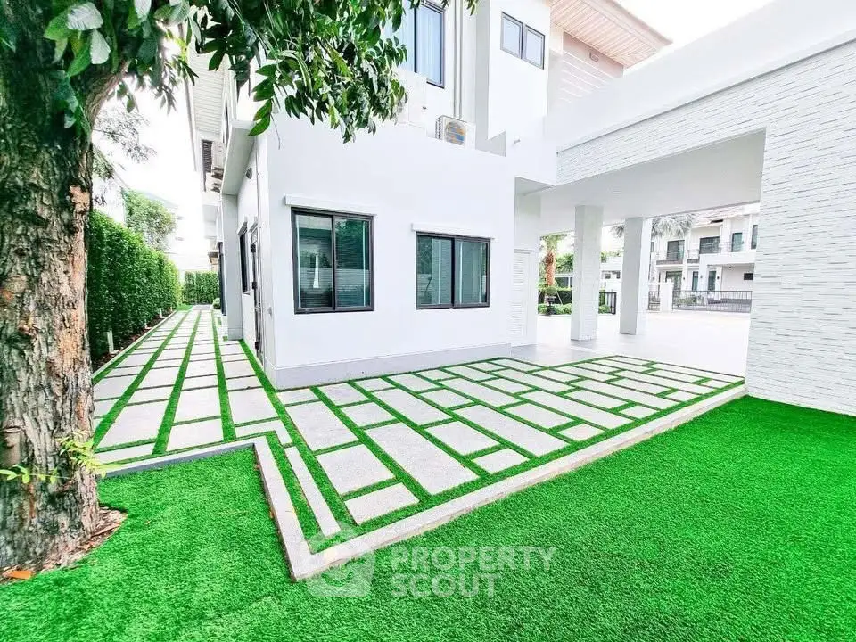 Modern white house with stylish paved driveway and lush green artificial grass.