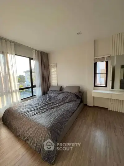 Spacious bedroom with large windows and modern decor, perfect for relaxation and comfort.