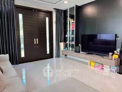 Modern living room with sleek black wall, large TV, and elegant double doors.