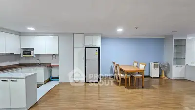 Spacious kitchen with dining area, featuring modern appliances and wooden flooring.