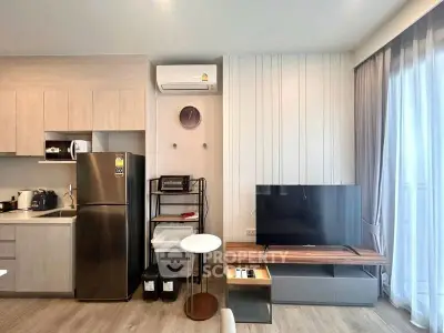 Modern living room with sleek kitchen, stainless steel fridge, and large TV, perfect for urban living.