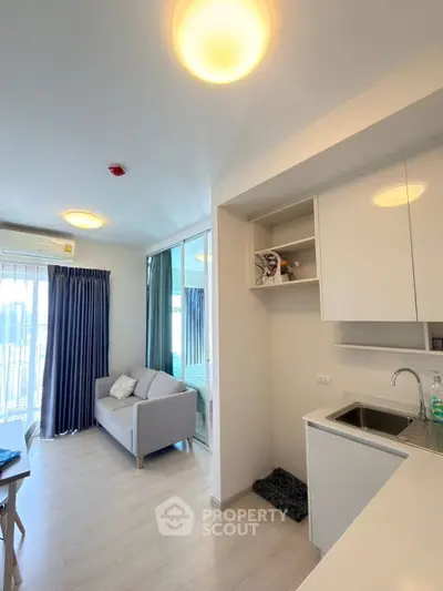 Modern apartment interior with open kitchen and cozy living area, featuring bright lighting and sleek design.