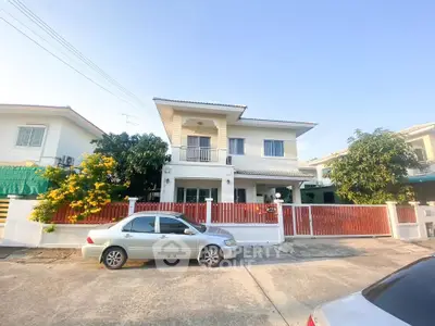 Charming two-story house with red fence and driveway in a sunny neighborhood.