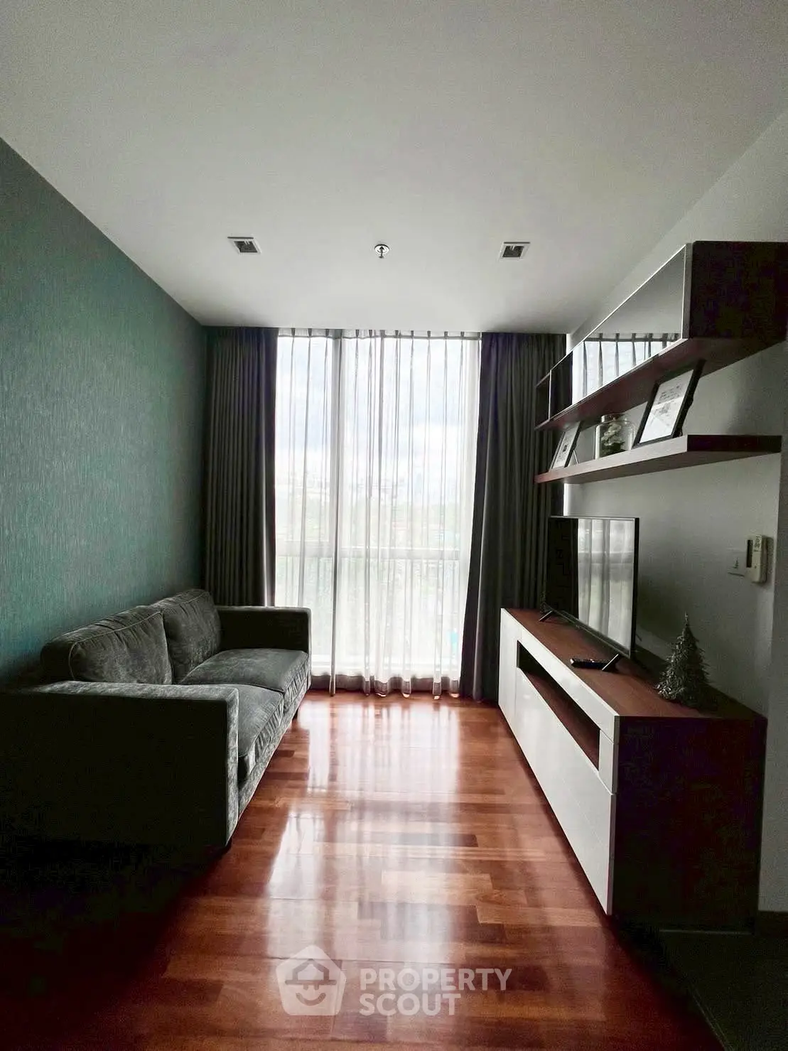 Stylish living room with modern sofa and entertainment unit, featuring floor-to-ceiling windows and elegant curtains.
