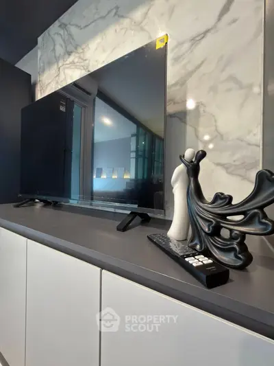 Modern living room with sleek TV setup and elegant decor on marble backdrop.