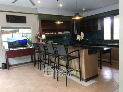Spacious kitchen with island and bar stools, featuring open layout and modern lighting.