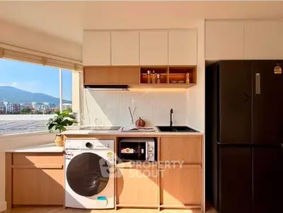 Modern kitchen with appliances and mountain view, featuring washing machine and sleek cabinetry.